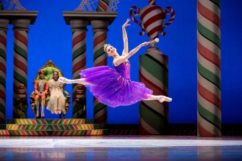 A ballerina dressed as the sugar plum fairy leaps across the stage with her arms outstretched in "The Nutcracker."