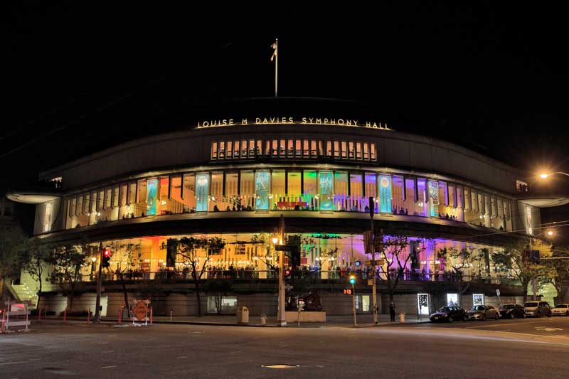 exterior image of Davies Symphony Hall lit up with rainbow lights at night