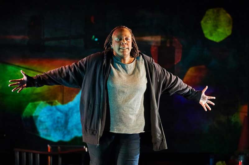 Dael Orlandersmith stands with her arms outstreached on stage in "In the Flood"