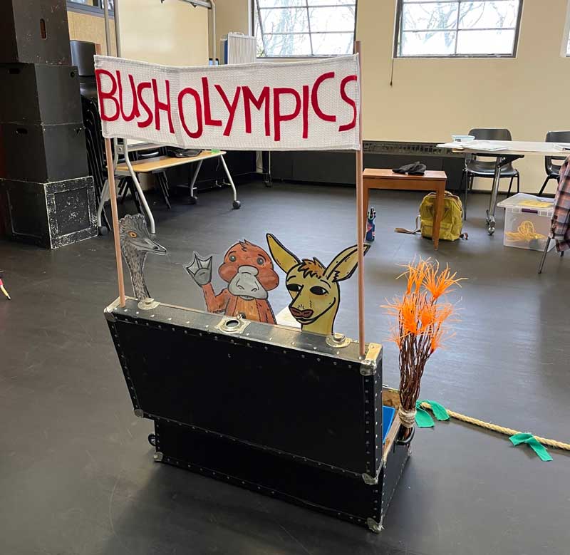 A small set piece that looks like a lemonade stand with a sign that says "Bush Olympics" with a cut out off a kangaroo behind it