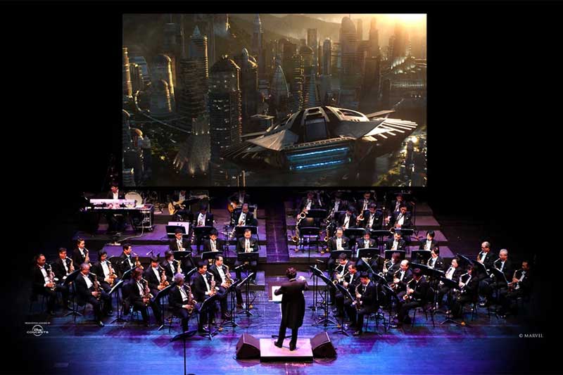 an audience watches the black panther movie while an orchestra plays