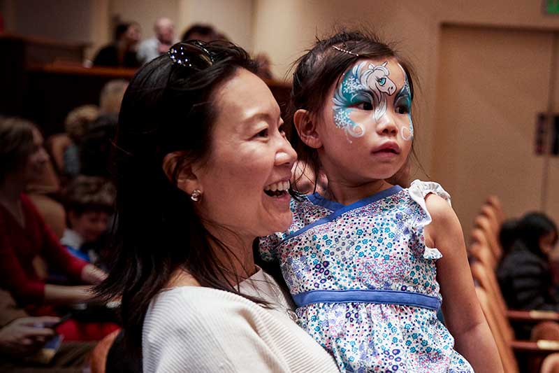 a woman laughs while holding a child in a blue dress