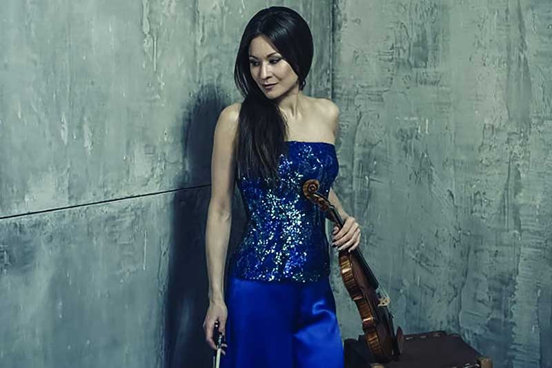 violinist Arabella Steinbacher wears a bright blue outfit holding her violin