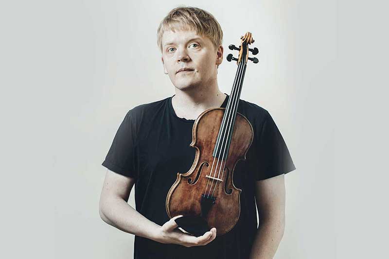 violinist Pekka Kuusisto holds his violin in front of himself