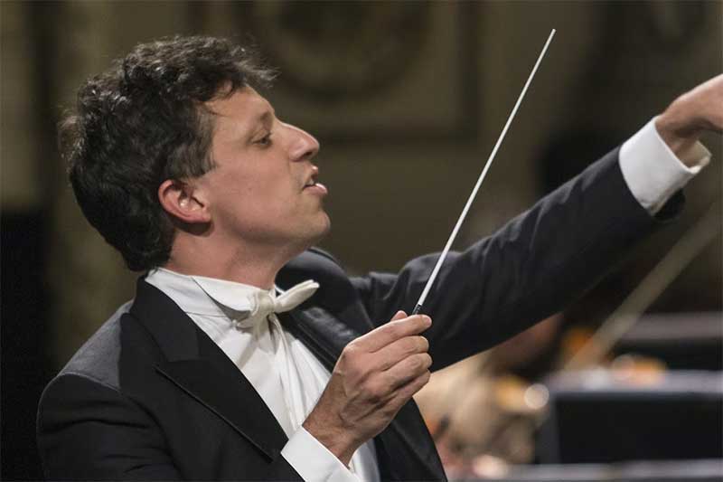 conductor Paolo Bortolameolli looks of into the distance as he conducts