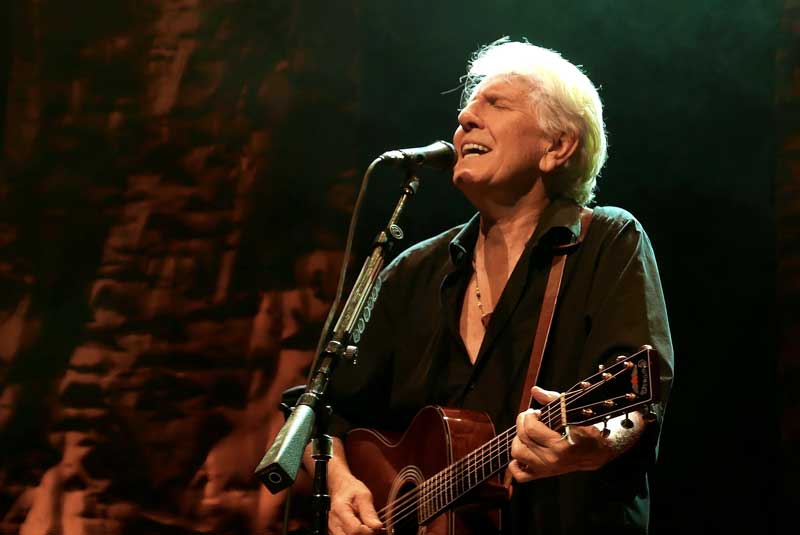 an older man plays guitar and sings into a microphone
