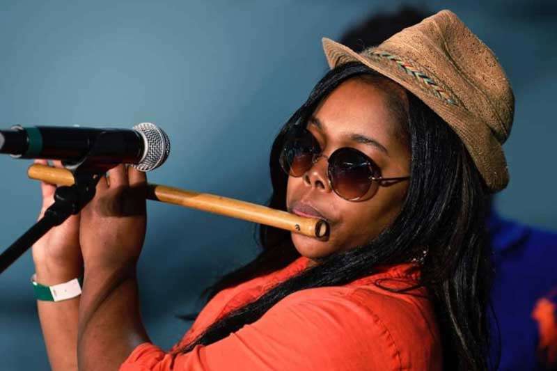 a woman plays a flute in front of a microphone