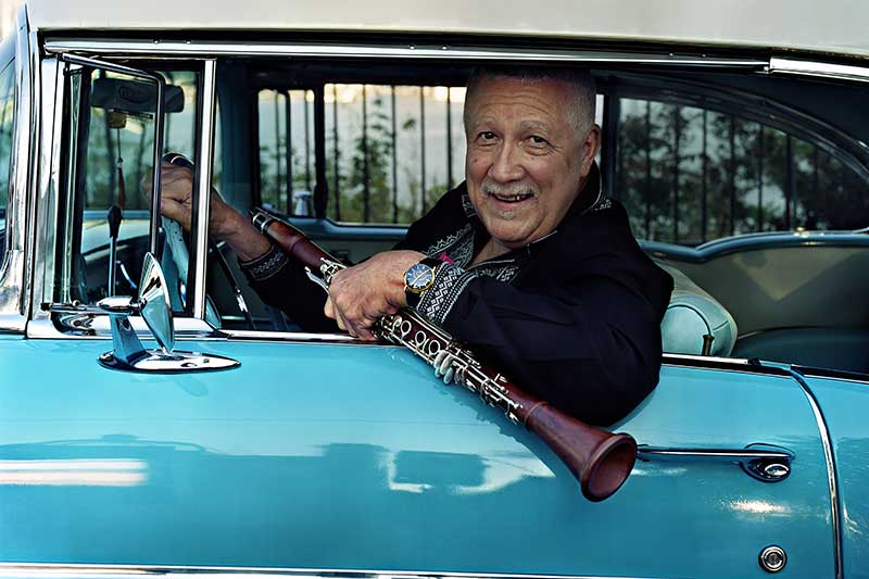 musician Paquito D'Rivera sits in a classic blue car