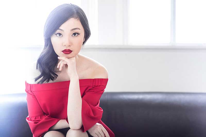 singer Ying Fang sits on a coach in a red dress