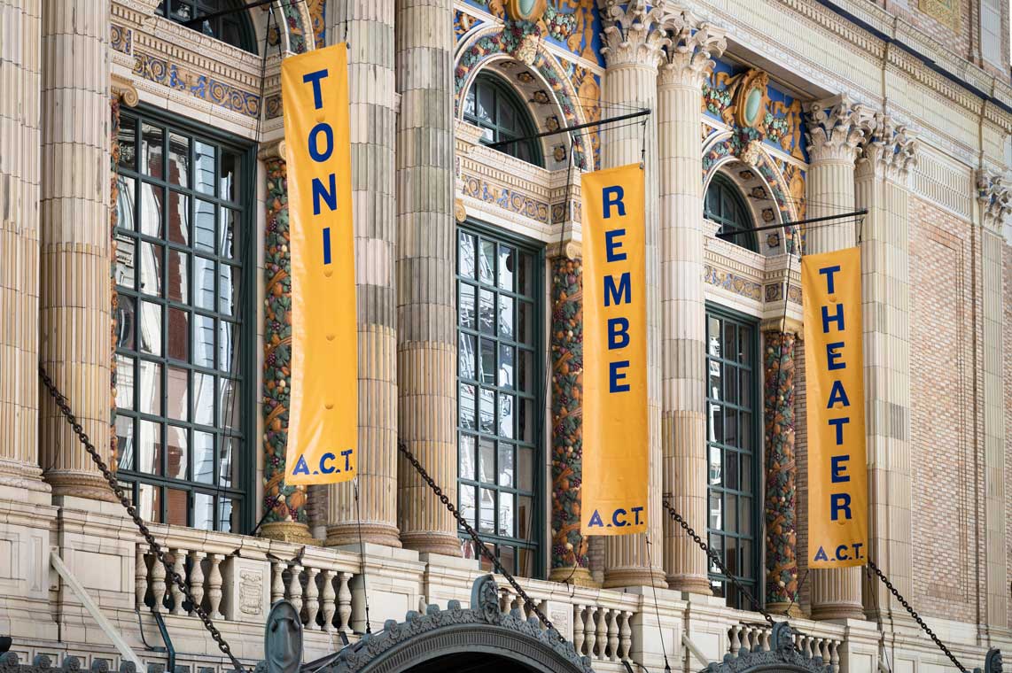 the exterior of a stone theater facade with banners with the name toni rembe theater