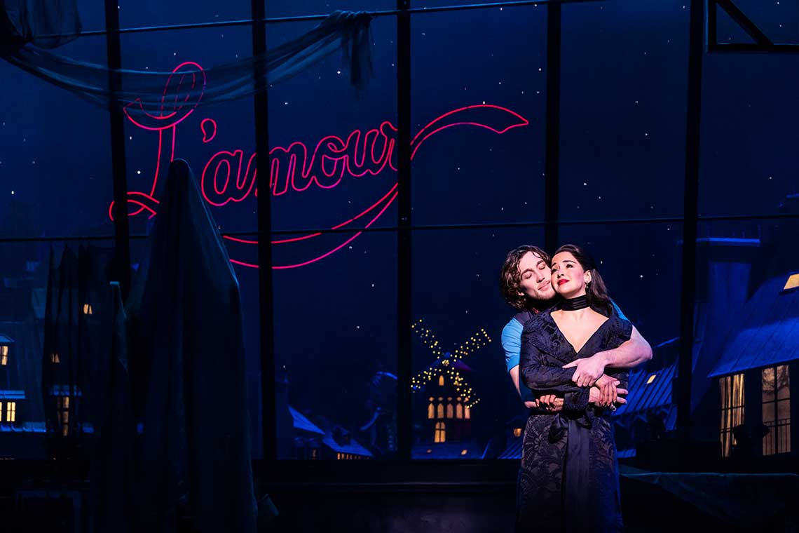 a man and woman embrace each other in front of a large sign that say l'amour