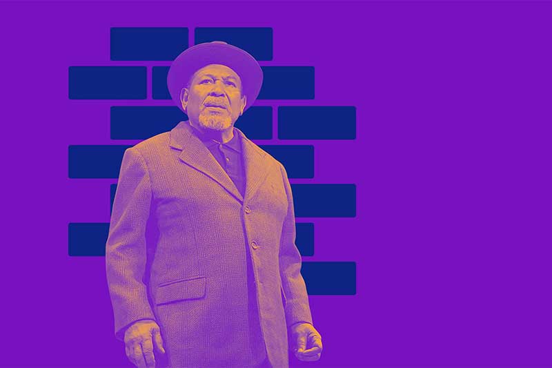 A photo of August Wilson superimposed on a purple background with bricks in the back.