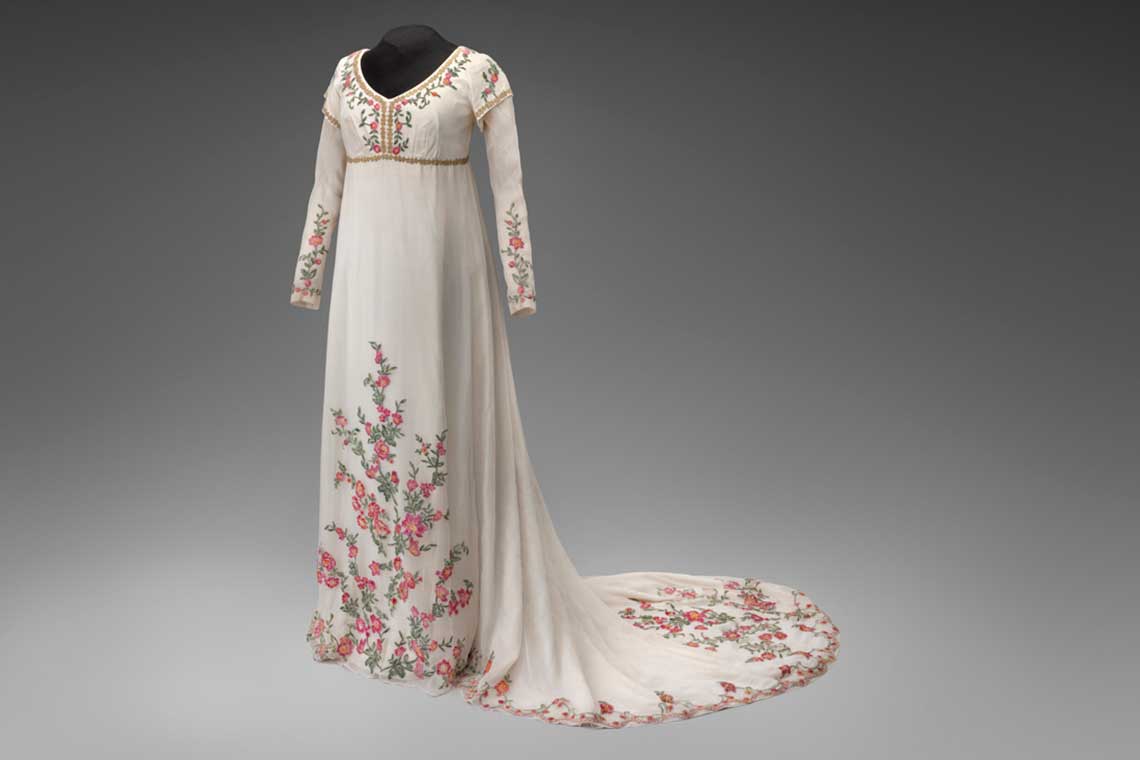 A simple white gown with a train and flowers embroidered on the sleeves and bottom.