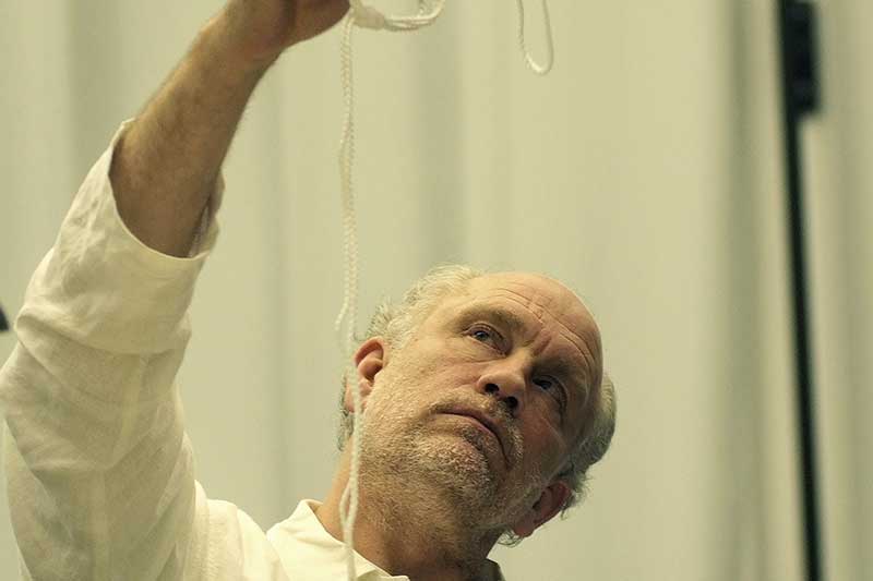 The actor John Malkovich holds a sting in his hand and looks at it