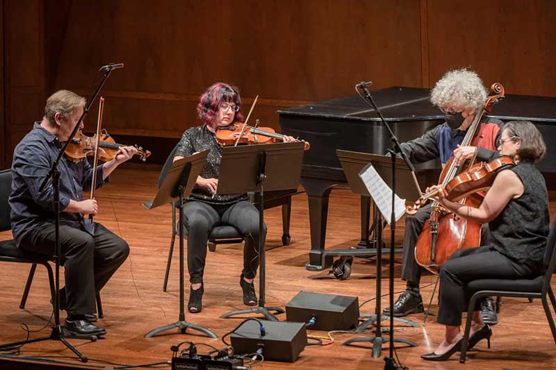 A chamber string quartet plays on stage.