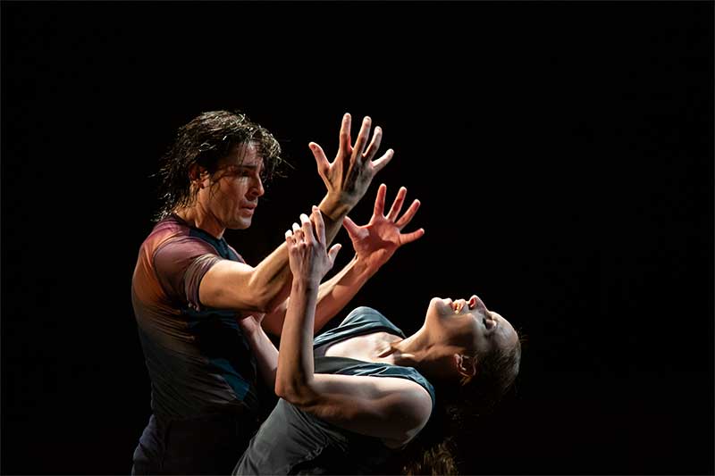 A woman and man dance. Their hands are held out to each other.