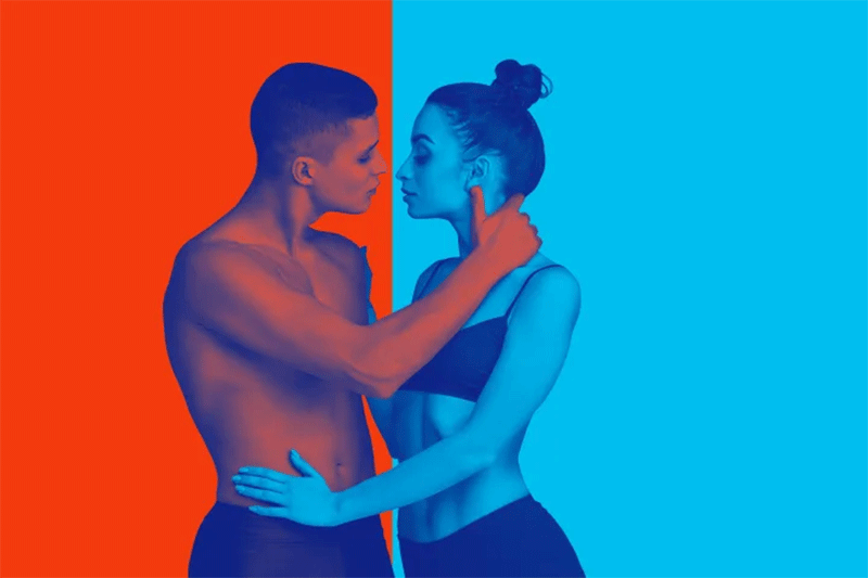 A man and woman embrace in front of two different color backgrounds.
