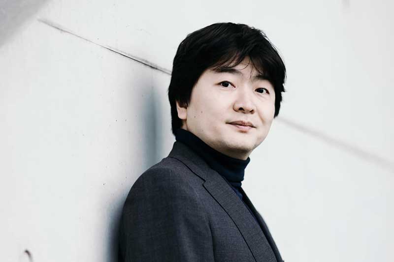 An man stands against a wall.