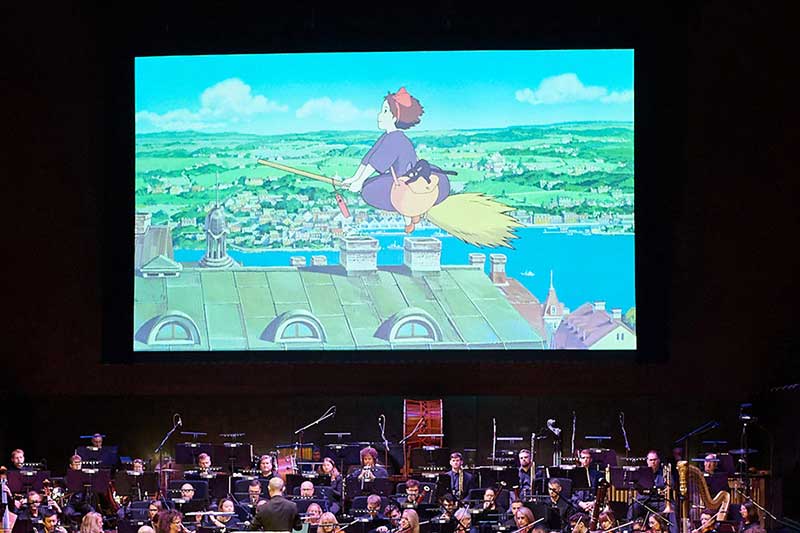 The SF Symphony plays on stage while a Ghibli movie plays above.