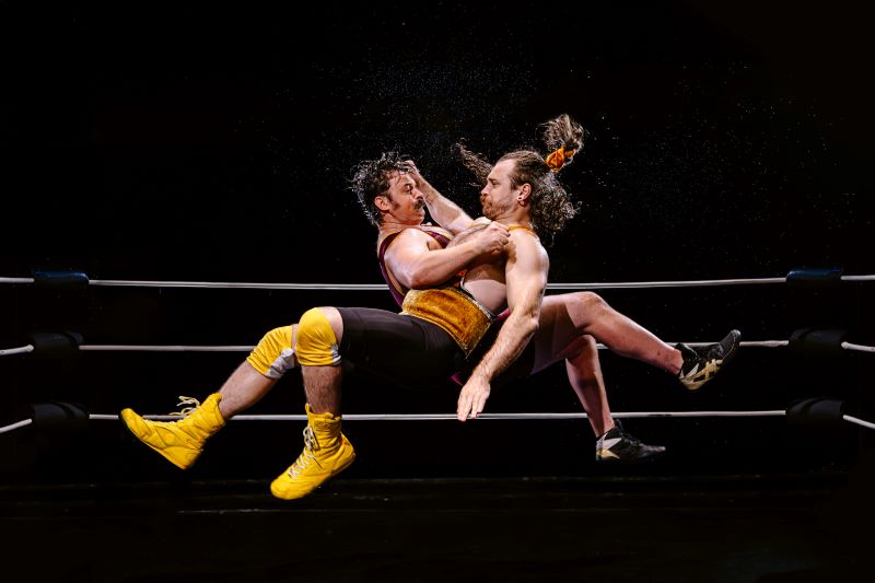 Two men wrestling. They are in the air grappling with each other.