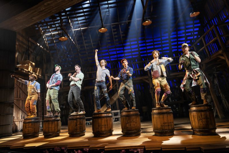A group of people stand in a row on wooden barrels.