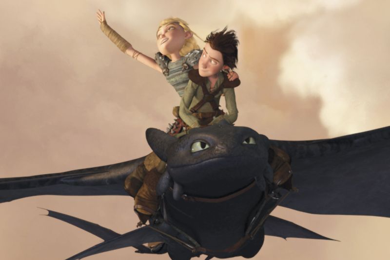 A movie still from How to Train Your Dragon with toothless flying in the air and Hiccup and Astrid on his back.