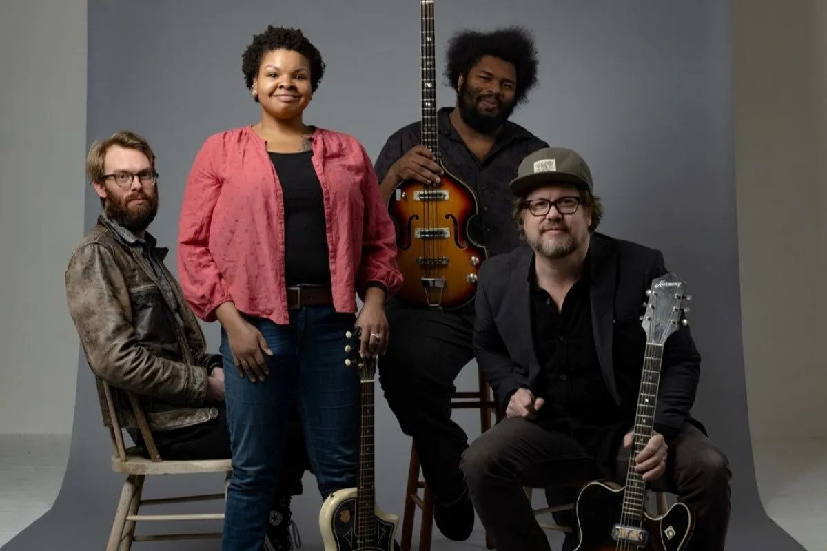 A group of four musicians pose for a press shot.