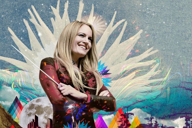 Eimear Noone stands smiling with her arms crossed in front of an illustrated colorful background.