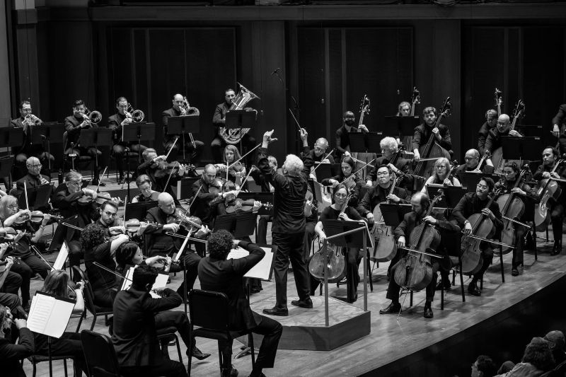A black and white image of the Seattle Symphony onstage performing