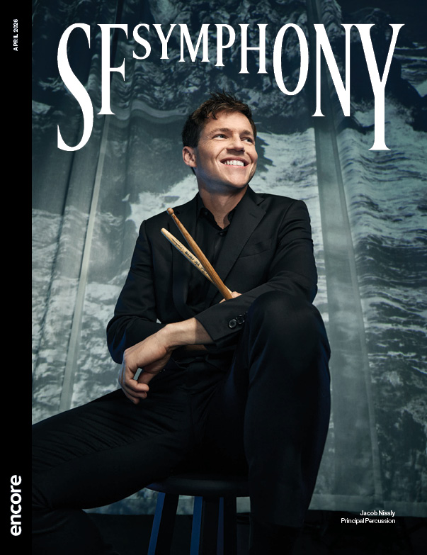 Jacob Nissly, Principle Percussion holds his drumsticks, seated on a stool. | Cover of SF Symphony April 2026