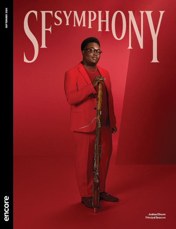 Joshua Elmore in a red suit with his bassoon, on a red background. | Cover of SF Symphony September 2026